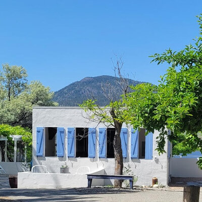 Greek-style outdoor kitchen with four large blue shutters.